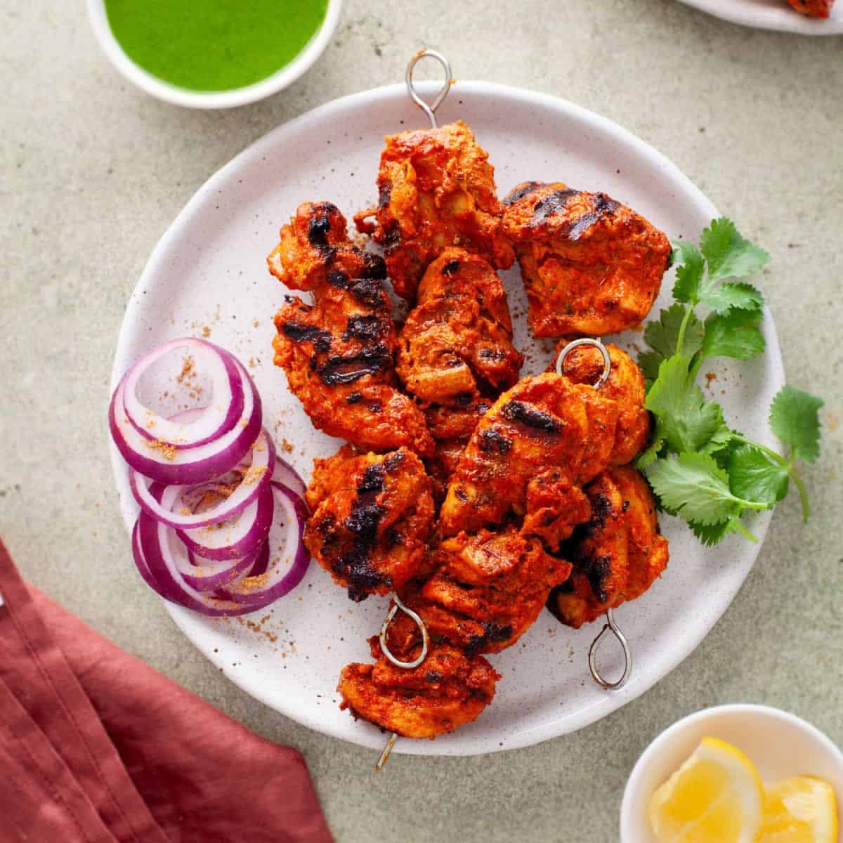 Gegrilltes Chicken Tikka am Spieß mit roten Zwiebeln und Koriander