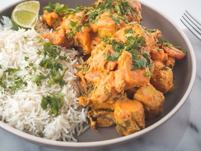 Cremiges Curry mit Koriander, serviert mit gedämpftem Basmatireis und einer Limettenspalte