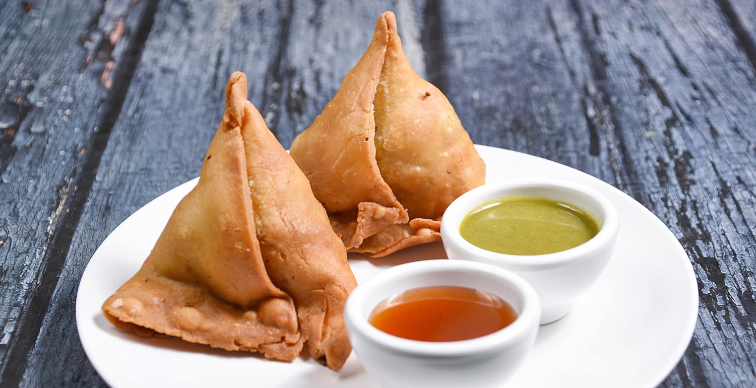 Knusprige Samosas serviert mit Tamarinden- und Minzsoße